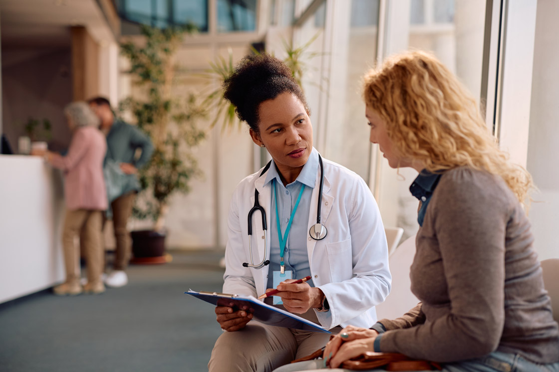 A doctor consults with a woman inside of a waiting area of a building